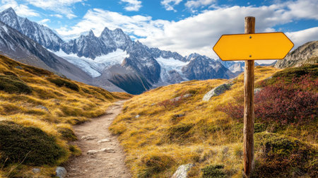 Majestic mountain views with a hiking trail sign leading toward snow-covered peaks, offering space for inspirational text.の素材