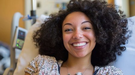 A cheerful young woman with curly hair beams with happiness while resting in a hospital room, embodying optimism and strength during her recovery process.の素材