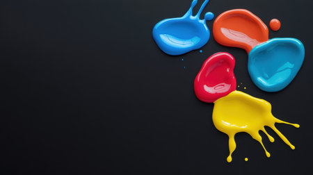 Vibrant paint droplets sit against a dark background, showcasing a dynamic blend of blue, red, yellow, and orange, perfect for artistic and creative projects.の素材