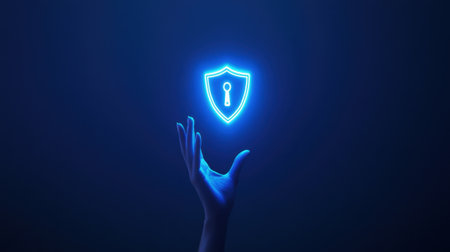 A visually striking image featuring a glowing shield icon symbolizing security, held by a hand against a dark backdrop, representing technology and protection in the digital era.の素材