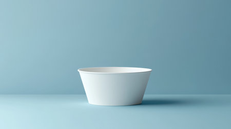 A minimalist white bowl sits elegantly on a soft blue surface, creating a serene and modern aesthetic. Ideal for showcasing simplicity in design and decor.の素材
