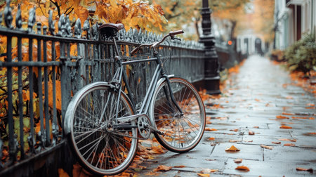 A vintage bicycle rests against a decorative iron fence surrounded by vibrant autumn leaves. This picturesque scene captures the essence of a tranquil park path during the fall season, inviting exploration and reflection.の素材