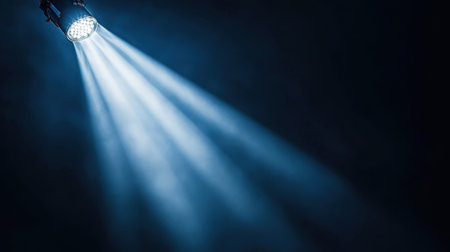 A stunning spotlight casts bright beams through the dark space, creating a dramatic and moody atmosphere perfect for theatrical performances or artistic photography.の素材