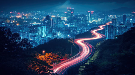 Stunning night view of a vibrant city skyline with a winding road. Light trails from moving vehicles create a dynamic contrast against urban lights, showcasing beauty.の素材
