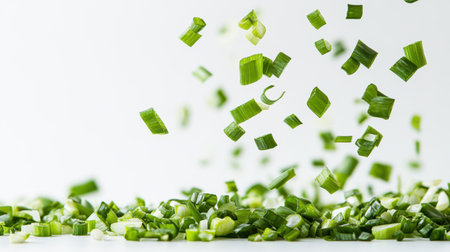 Chopped fresh green onions cascade dramatically against a bright white background, showcasing vibrant colors and textures perfect for culinary creations.の素材