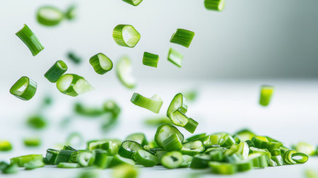 A dynamic composition of freshly chopped green onions floating against a light background, showcasing vibrant colors perfect for culinary use and food photography.の素材