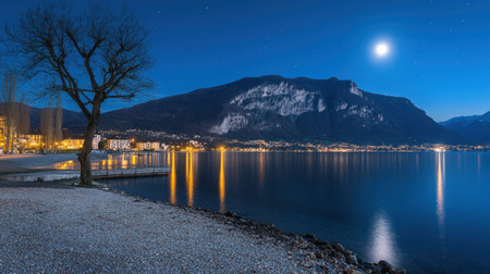 A tranquil night scene showcasing a lake surrounded by majestic mountains, illuminated by moonlight. Stars twinkle above, reflecting on the water surface.の素材