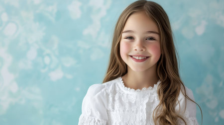 A cheerful young girl with long hair smiles warmly, showcasing innocence and joy. The soft blue background enhances her natural beauty in this captivating portrait.の素材
