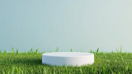 A minimalist white cylinder sits in lush green grass under a clear blue sky. This serene and peaceful setting offers a perfect backdrop for various creative projects.の素材