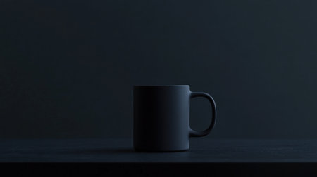 A minimalist black mug sits on a dark table, elegantly contrasting with its surroundings. The composition evokes a sense of calm and simplicity, ideal for modern aesthetics.の素材