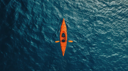 A vibrant orange kayak glides effortlessly over calm blue waters, showcasing a serene and adventurous escape into nature. Perfect for travel and outdoor activities.の素材