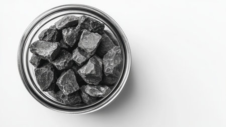 A striking close-up image of black rock stones displayed in a clear glass jar set against a minimalist white background, ideal for showcasing natural textures and earthy elements.の素材