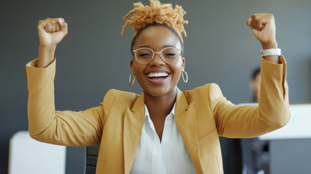 A happy businesswoman celebrates her achievements with raised fists, exuding confidence and joy in a contemporary office setting, emphasizing empowerment and motivation.の素材