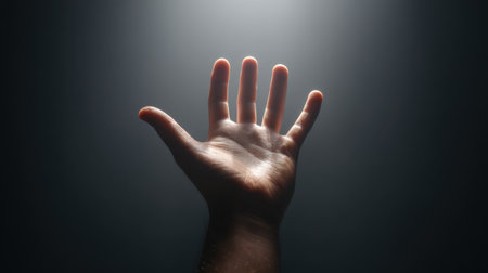 This captivating image features a hand reaching toward a faint light, set against a dark background, symbolizing hope and aspiration in a tranquil and minimalist manner.の素材