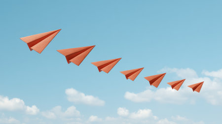 A captivating scene of orange paper airplanes soaring through a bright blue sky with fluffy clouds, symbolizing freedom, creativity, and adventure in flight.の素材