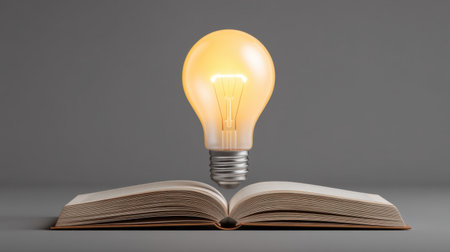 A glowing light bulb hovers above an open book, symbolizing the spark of ideas and creativity. This minimalist composition evokes themes of inspiration and enlightenment.の素材