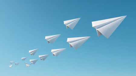 A stunning display of white paper planes soaring high in a blue sky, symbolizing creativity, teamwork, and the pursuit of dreams in an inspiring and imaginative scene.の素材