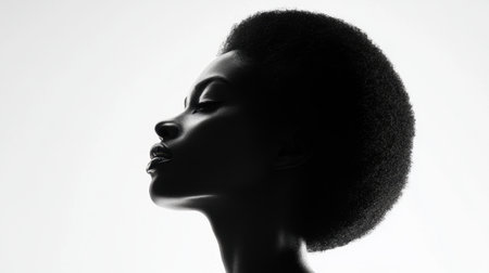 A striking silhouette of a woman with natural hair, elegantly showcasing her profile against a soft light background, exuding beauty and confidence.の素材