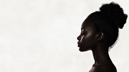 This image features a striking profile of a young woman with curly hair against a soft gray background, emphasizing beauty, elegance, and individuality.の素材