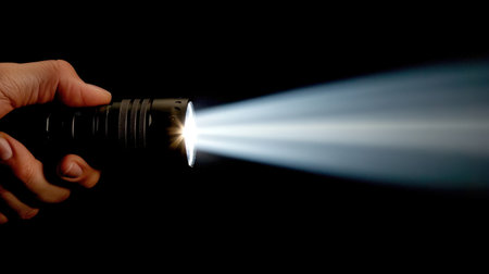A handheld flashlight emits a strong beam of light in a dark setting, showcasing its power and utility. Ideal for emergency situations and outdoor adventures.の素材