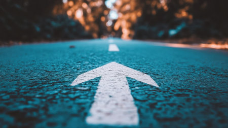 A close-up view of a white arrow painted on an asphalt road, symbolizing direction and guidance. The image captures a serene outdoor setting, inviting exploration.の素材