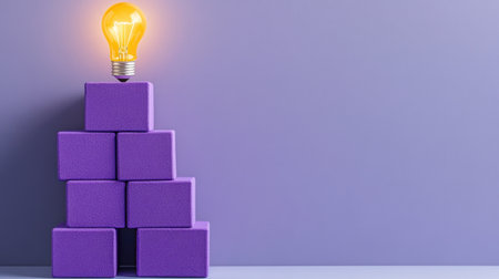 Purple blocks forming a pyramid with a lit bulb above, representing progress and learning growthの素材