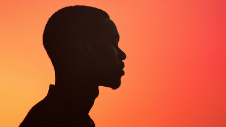 The silhouette of an African man in a thoughtful pose, against a gradient background symbolizing introspection and strength.の素材