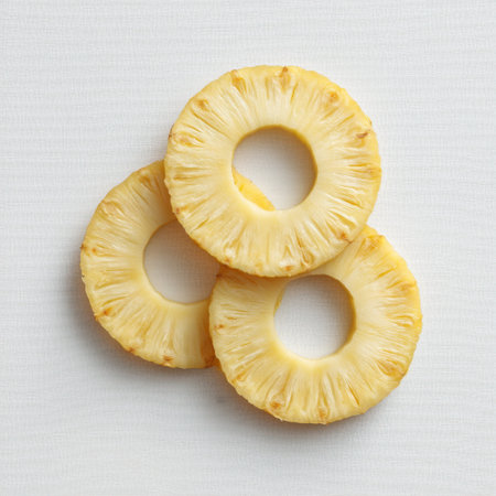 Bright and fresh pineapple rings arranged neatly on a light textured surface, perfect for presentations related to cooking, healthy eating, or tropical themes.の素材