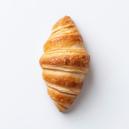 This image captures a beautifully baked golden croissant with flaky layers against a white background, ideal for food photography and culinary inspiration.の素材
