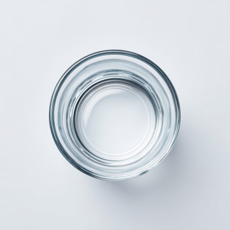 A clear glass bowl filled with pristine water sits on a smooth white background, symbolizing purity and simplicity. Ideal for wellness and refreshing themes.の素材