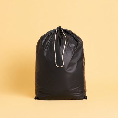 A black garbage bag stands prominently against a soft pastel background, illustrating effective waste storage solutions for households and emphasizing cleanliness and organization.の素材