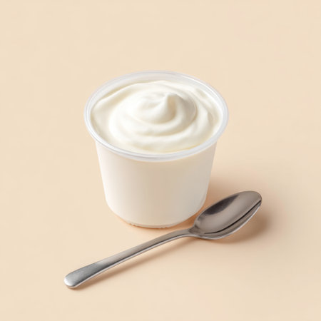 A simple yet elegant presentation of creamy yogurt in a clear cup complemented by a small silver spoon, ideal for healthy eating and food photography.の素材
