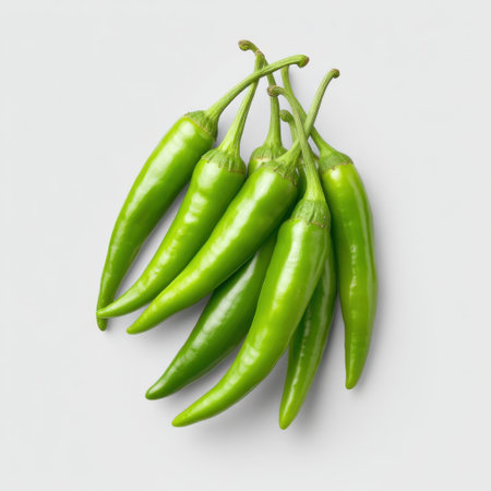 A cluster of fresh green chili peppers on a light background, perfect for showcasing culinary uses, healthy recipes, and vibrant food photography.の素材