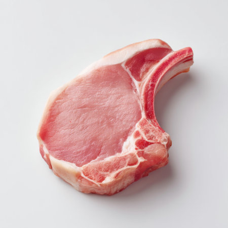 A fresh pork chop cut featuring a bone, presented on a clean white background. Ideal image for recipes and culinary inspiration focusing on meat quality and freshness.の素材