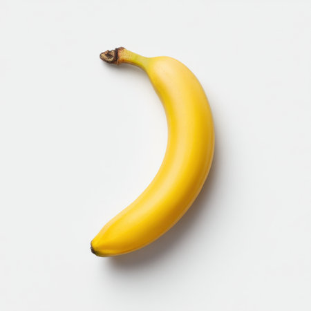 A vibrant yellow banana rests on a clean white background, showcasing its smooth texture and ripe appearance, ideal for healthy eating and culinary inspiration.の素材