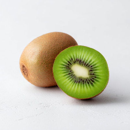A vibrant display of fresh kiwi fruit, showcasing one whole and one cut in half, revealing its bright green flesh and unique black seeds, perfect for healthy recipes.の素材