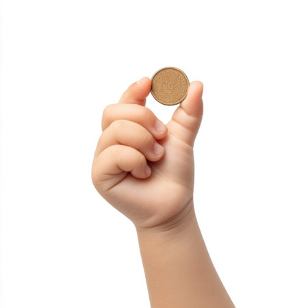 A child's hand showcases a shiny gold coin, representing the importance of financial literacy and savings. The image explores themes of value, joy, and learning.の素材