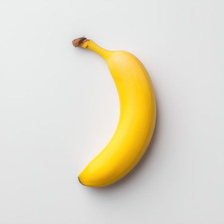 A vibrant yellow banana set against a clean white background, showcasing its natural curves and smooth texture, perfect for healthy eating themes and nutrition concepts.の素材