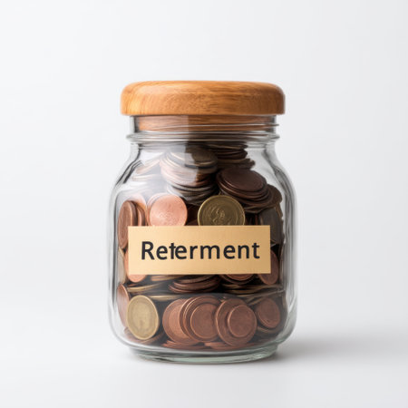 A glass jar filled with various coins labeled "Retirement," representing the importance of saving and planning for future financial security in a minimalist environment.の素材
