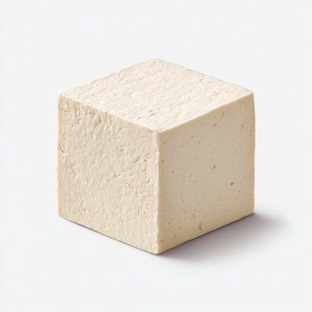 A fresh block of tofu resting on a plain background, ideal for promoting healthy eating, vegetarian recipes, and plant-based diet concepts in culinary contexts.の素材