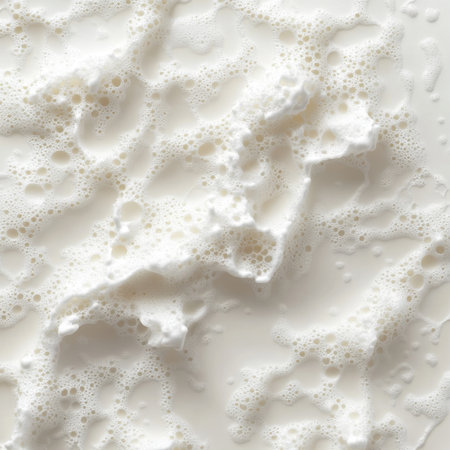 This image showcases a close-up view of fresh milk foam, presenting a creamy texture on a smooth white background, perfect for culinary and beverage projects.の素材