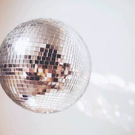 This image captures a disco ball suspended from a ceiling, casting vibrant light patterns in a soft-focus party atmosphere, enhancing the celebratory mood.の素材