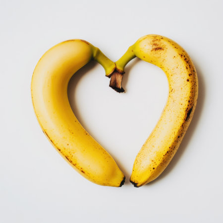 This vibrant image features two bananas artistically arranged to form a heart shape, highlighting themes of love and health. Ideal for food and wellness projects.の素材
