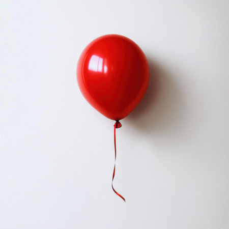 A vivid red balloon floating against a plain white background, evoking feelings of joy and celebration, ideal for festive events, party themes, or cheerful marketing.の素材