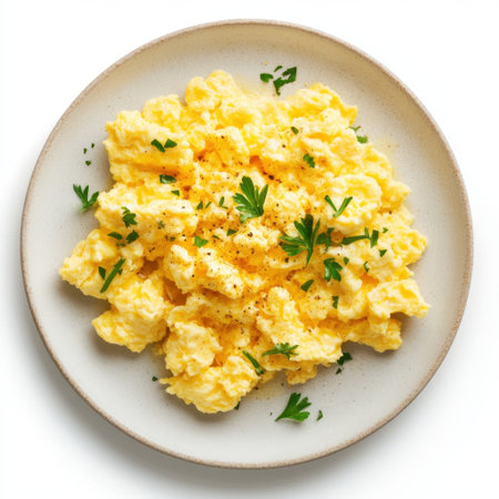 Scrumptious creamy scrambled eggs are beautifully presented on a white plate, garnished with parsley and black pepper, ideal for breakfast or brunch enjoyment.の素材