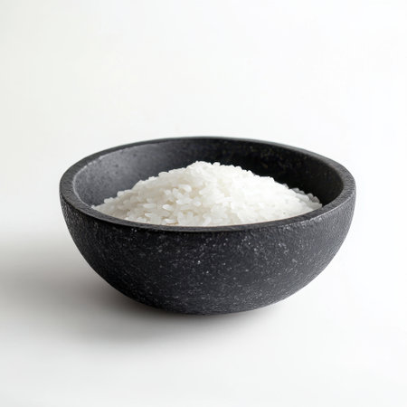 This image showcases a close-up view of white rice in a stylish black bowl against a clean white background, perfect for food-related projects and culinary uses.の素材