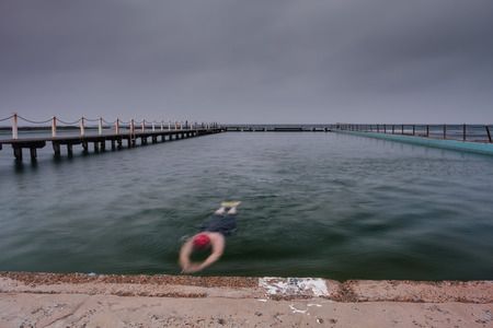 Swimmer at an ocean pool under a dark sky