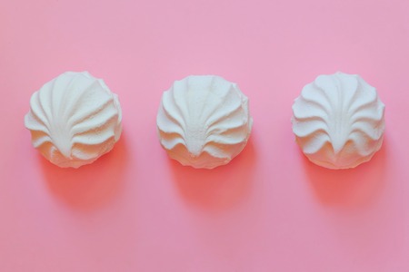 three white marshmallows lying on a pink background