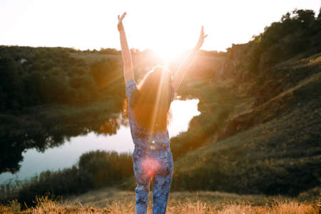 beautiful girl stands on a mountain and looks at the sunset
