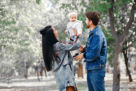 The family walks in the park, the mother keeps the little daughter above her head, the father takes care of the familyの写真素材